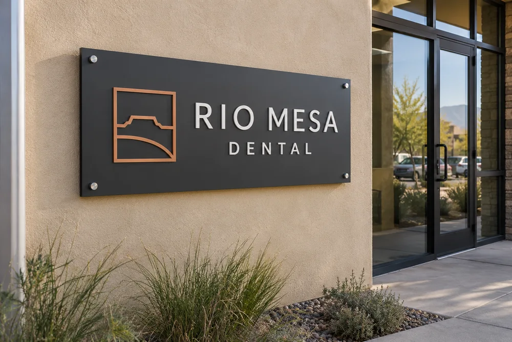 Rio Mesa Dental dimensional lettering on a charcoal wall-mounted panel beside an office entrance